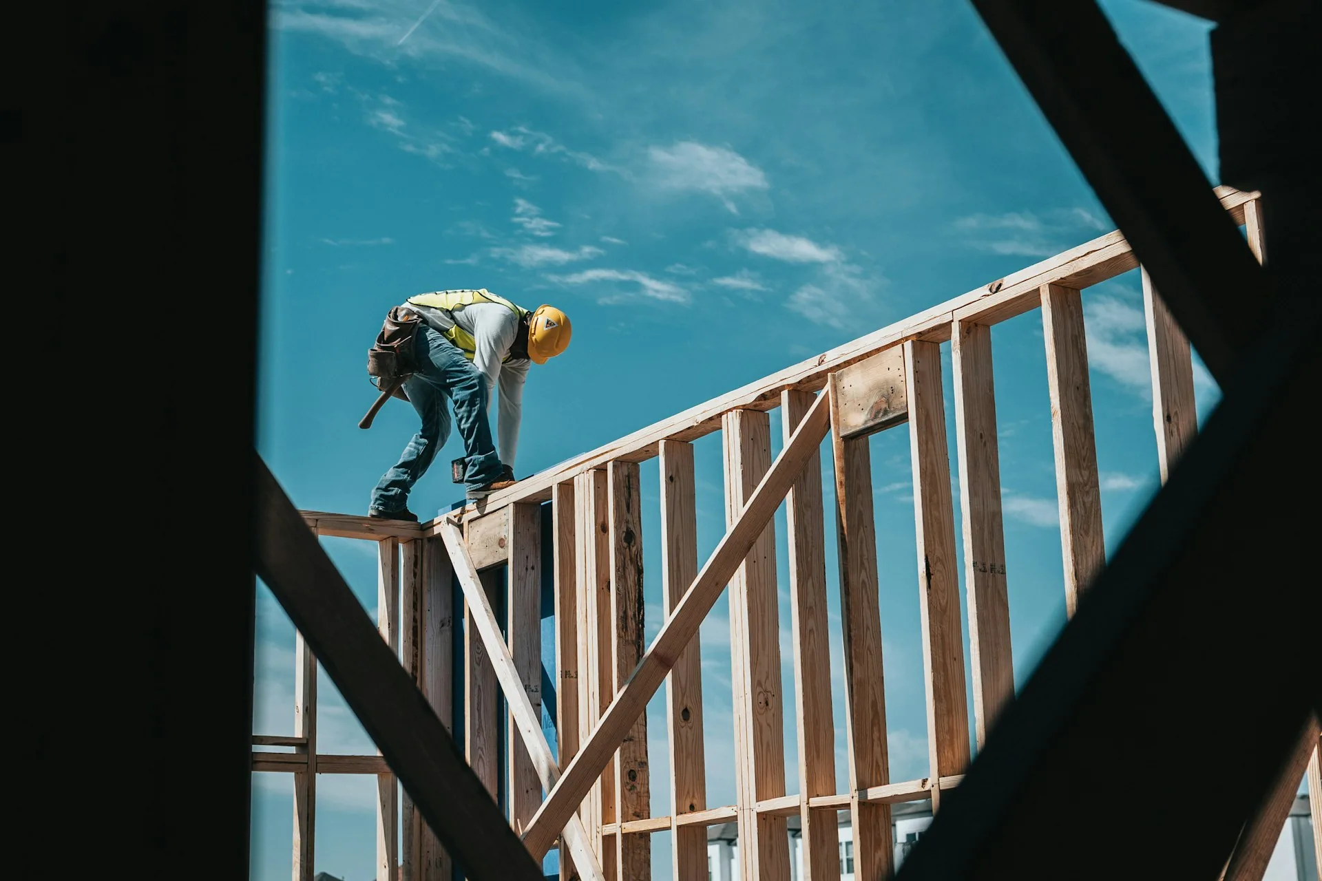 Framer working on a wood-framed wall against the sky
